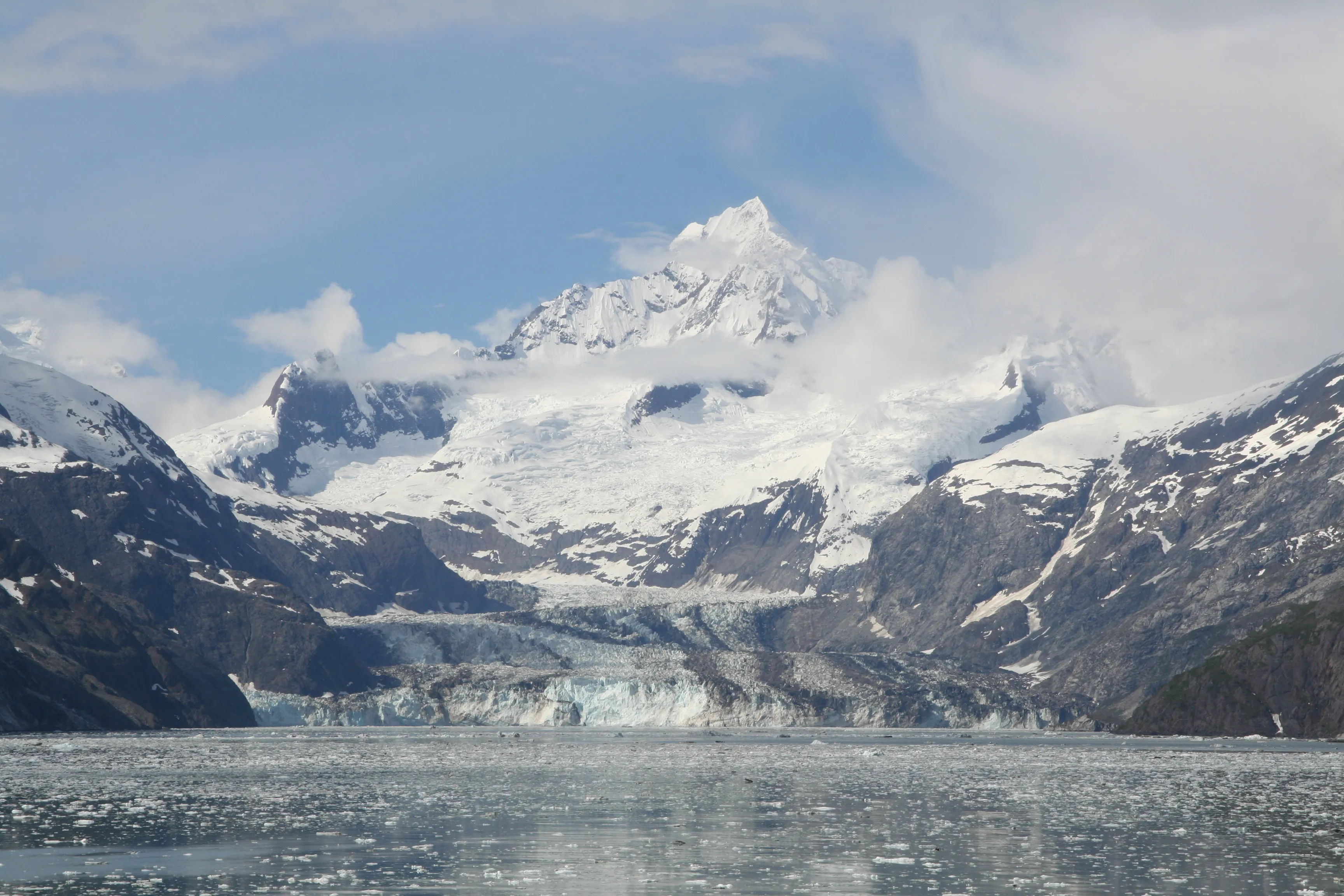 Johns Hopkins Glacier flowing into Glacier Bay beneath snow-covered peaks in Alaska