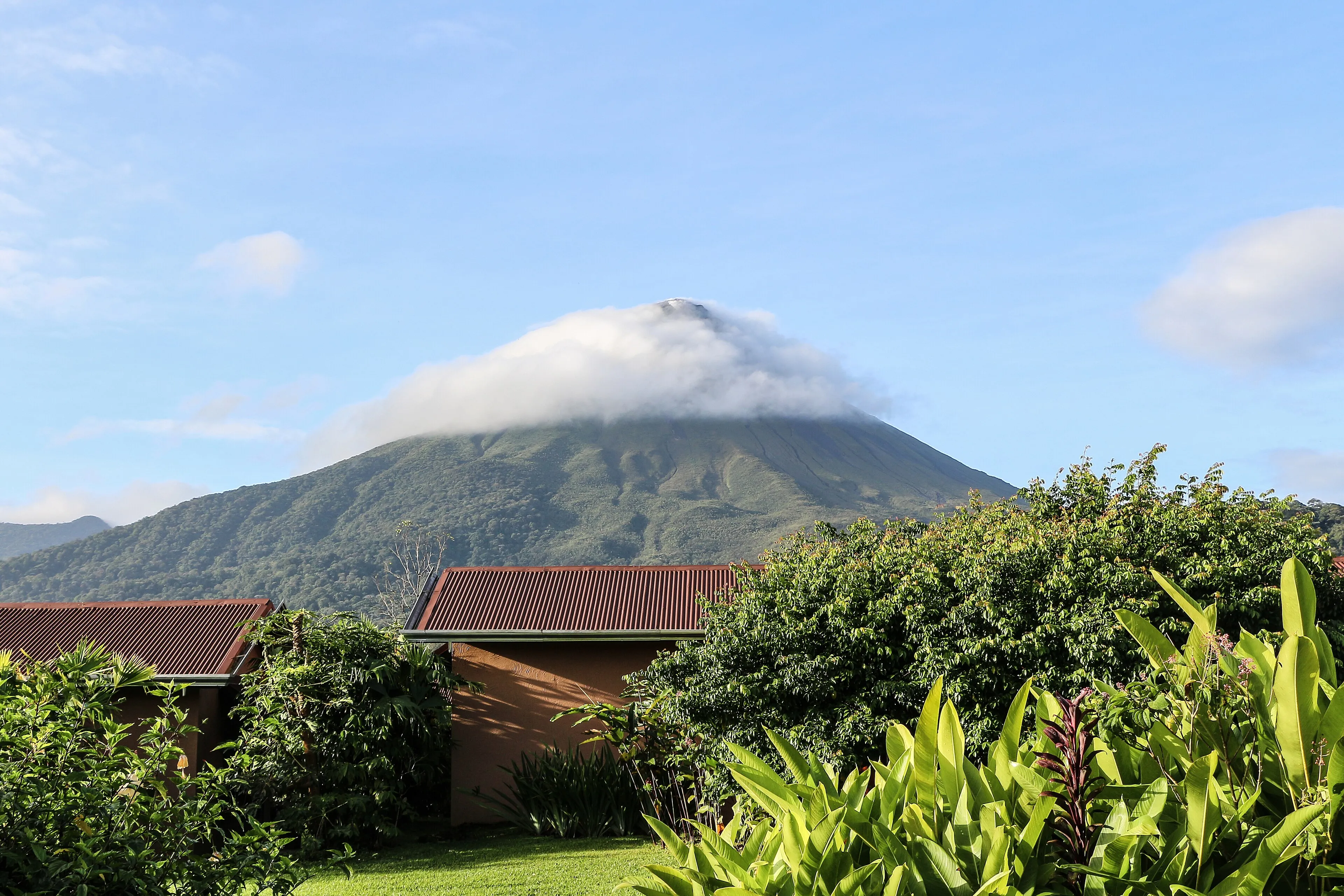 Cone of Arenal Volcano rising above green gardens near La Fortuna, Costa Rica