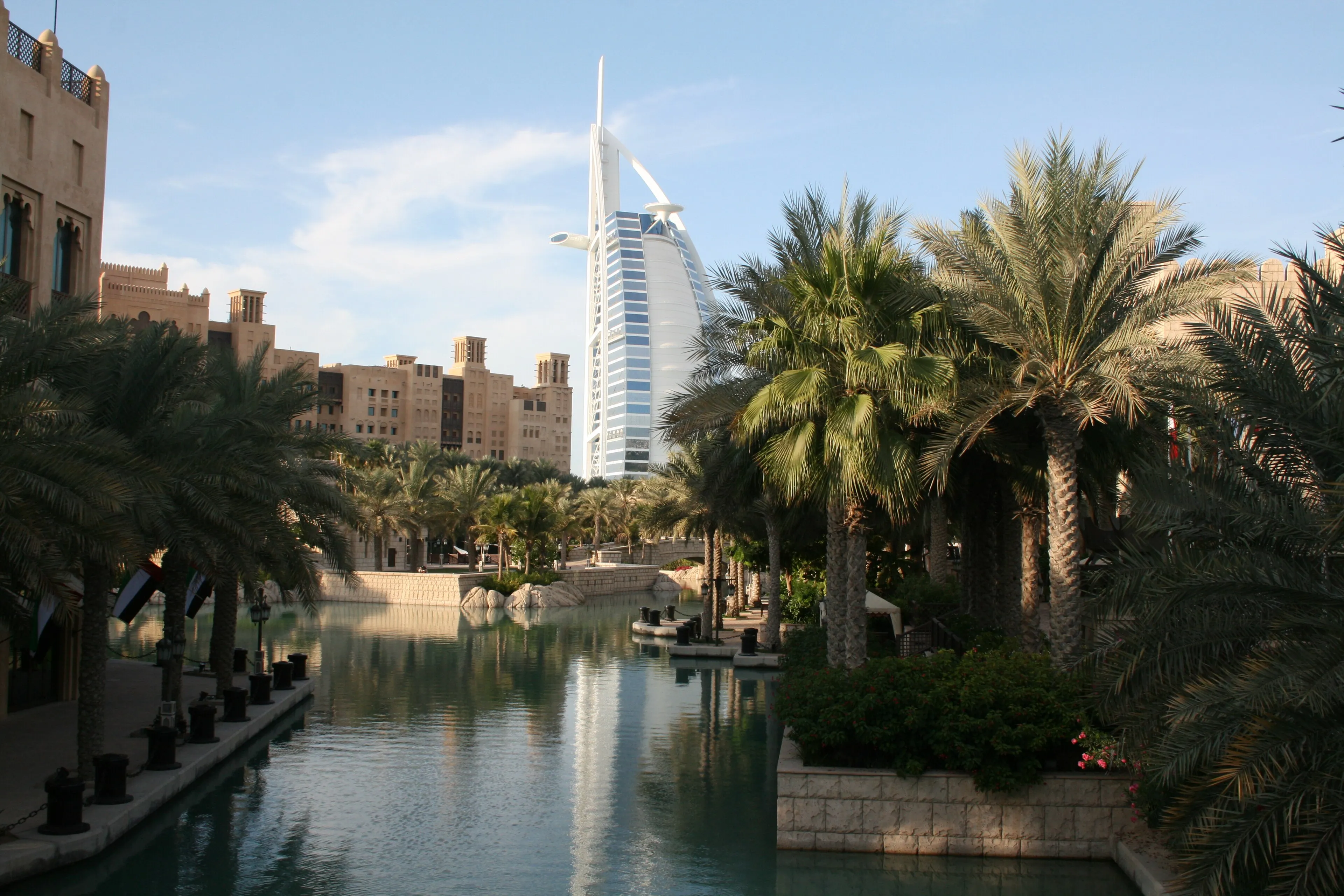 Palm-lined waterway at Madinat Jumeirah with the sail-shaped Burj Al Arab tower beyond, in Dubai
