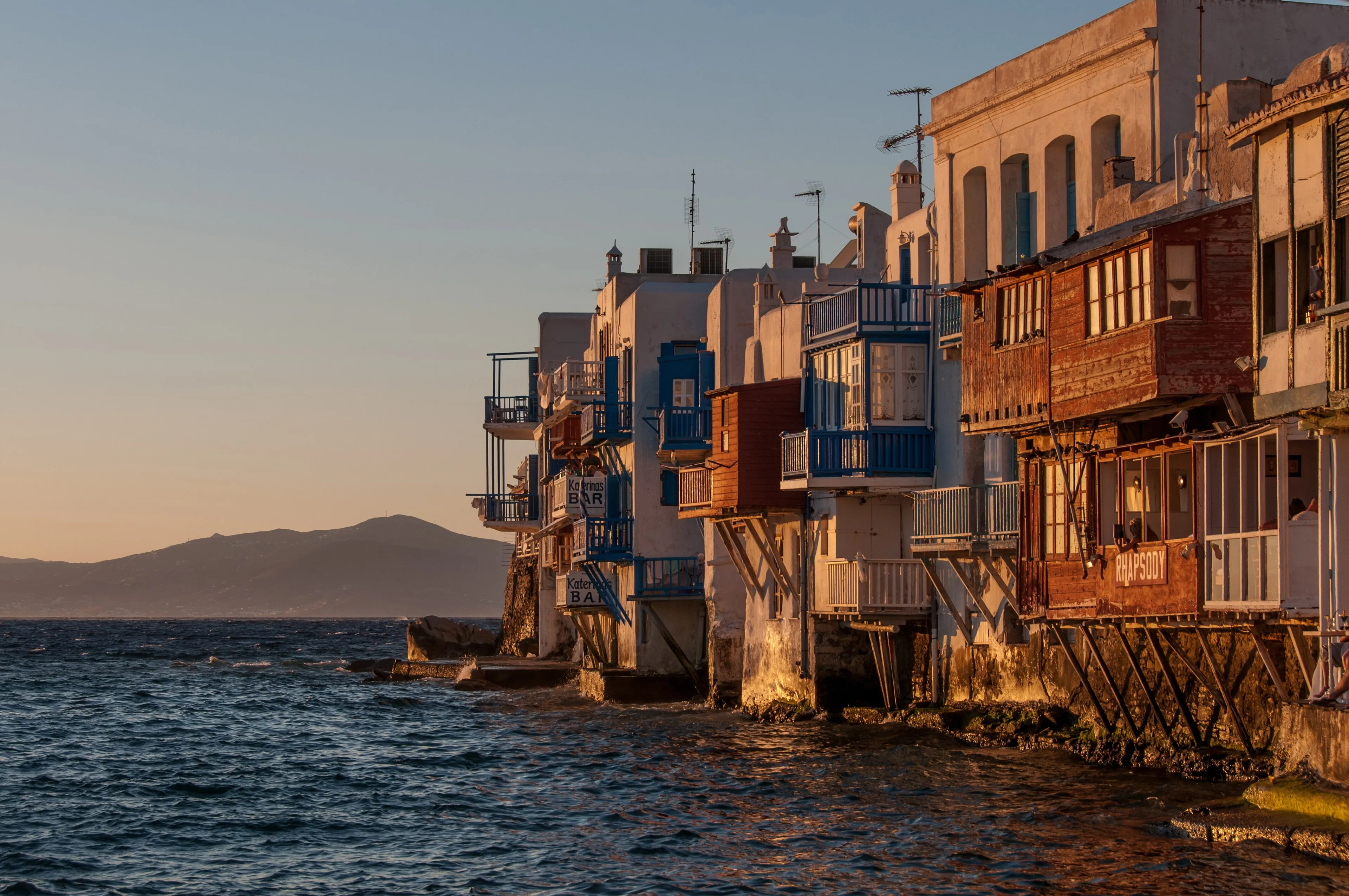 Colorful waterfront houses of Little Venice on Mykonos glowing at sunset above the sea