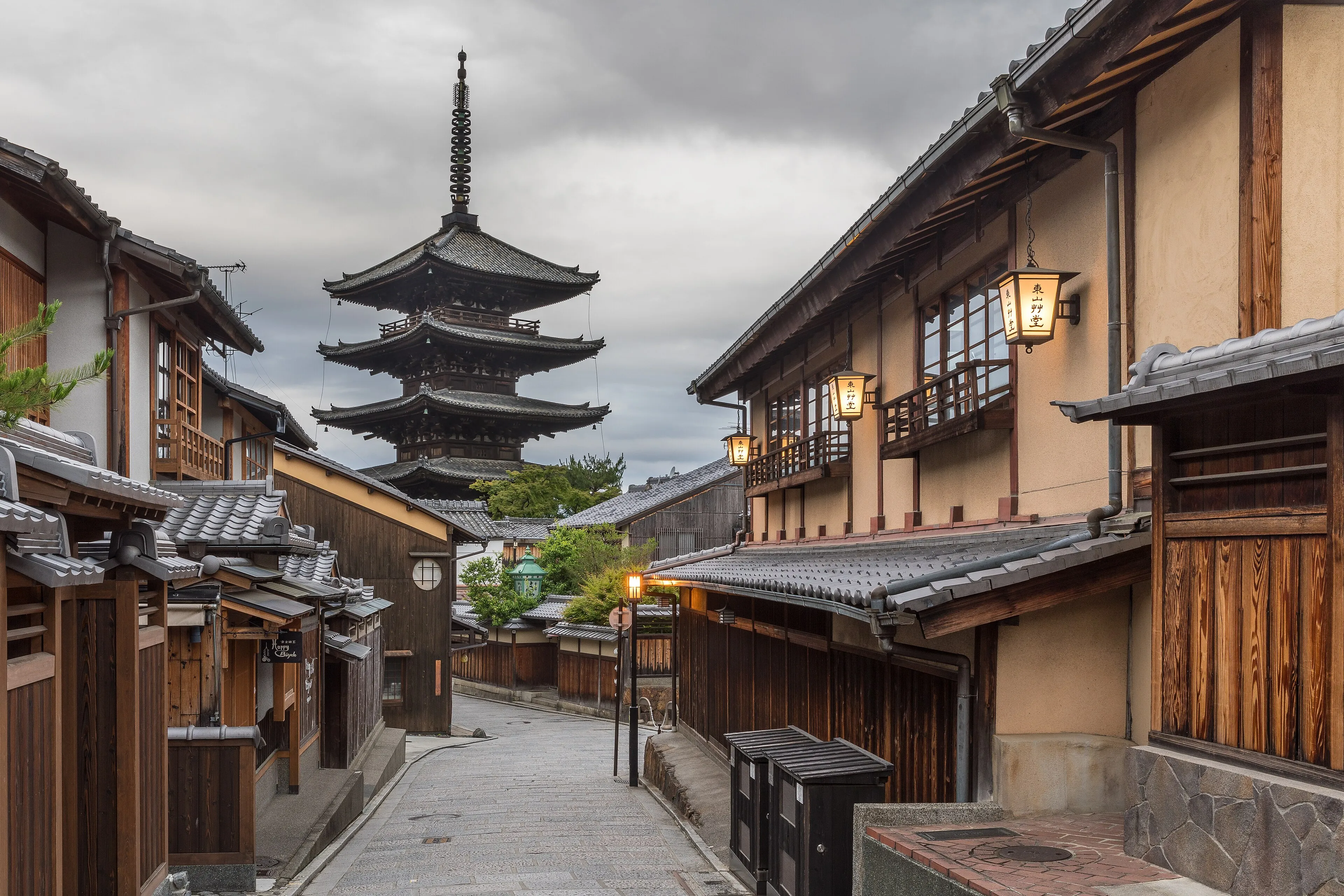Lantern-lit Yasaka-dori street in Kyoto at dawn, with the five-story Yasaka pagoda above traditional wooden houses