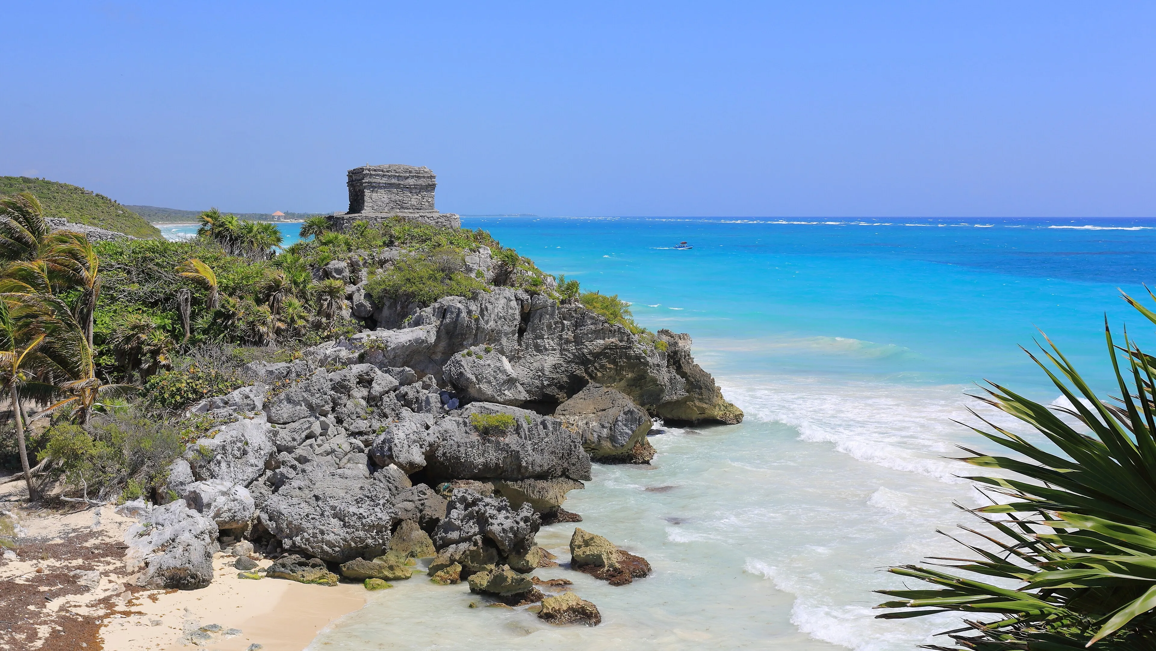 The Maya Temple of the God of the Winds at Tulum, on a rocky headland above a small beach and the turquoise Caribbean