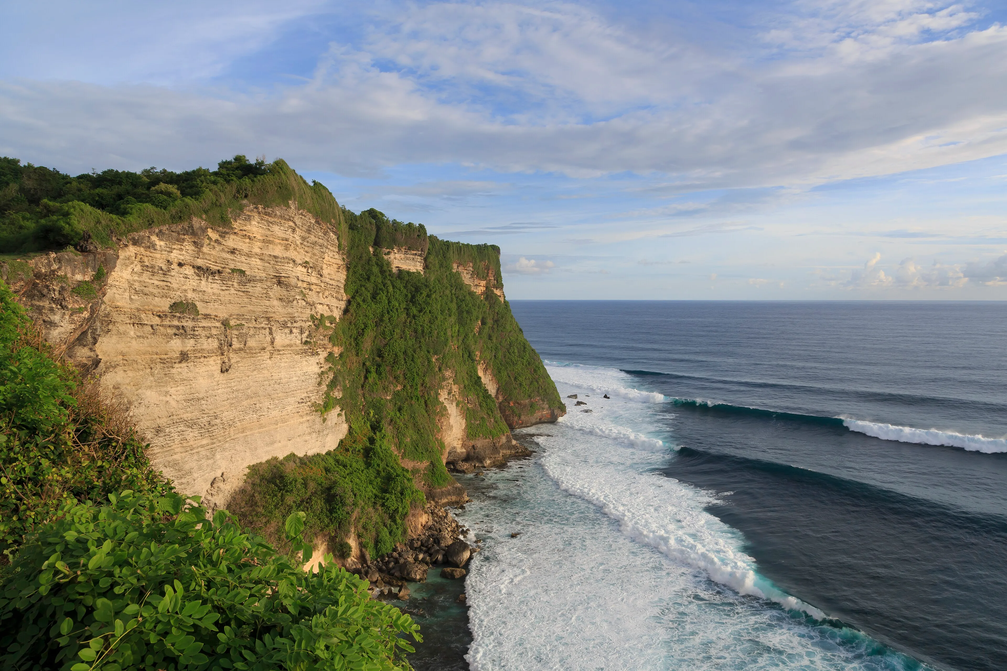 Limestone cliffs covered in green above the surf at Uluwatu, on Bali's southern tip
