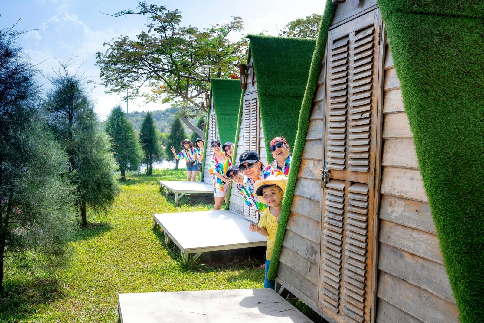 A cheerful family having fun outside colorful cabins in a sunny park setting.